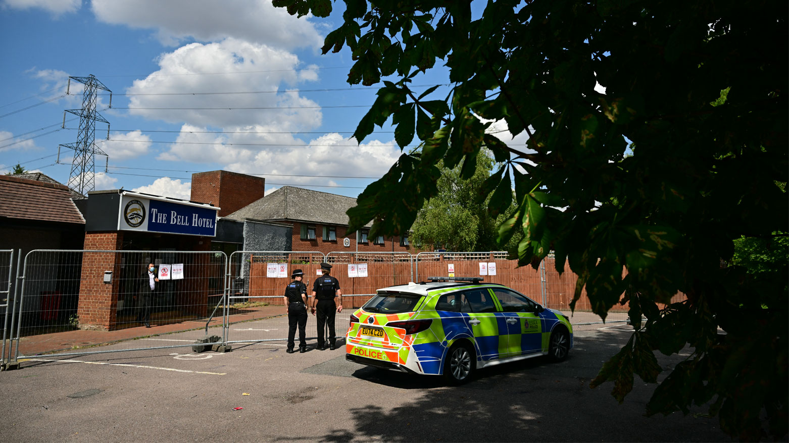 ضباط الشرطة عند سياج فندق "ذا بيل"، الذي يُعتقد أنه يؤوي طالبي لجوء، في إيبينغ، شمال شرقي لندن (فرانس برس)