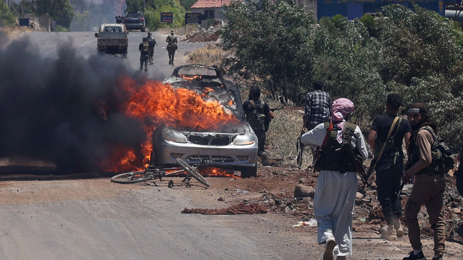 Bedouin and tribal fighters deploy as a car burns at the western entrance of Syria's Druze heartland of Sweida on July 18, 2025. (Photo: AFP)