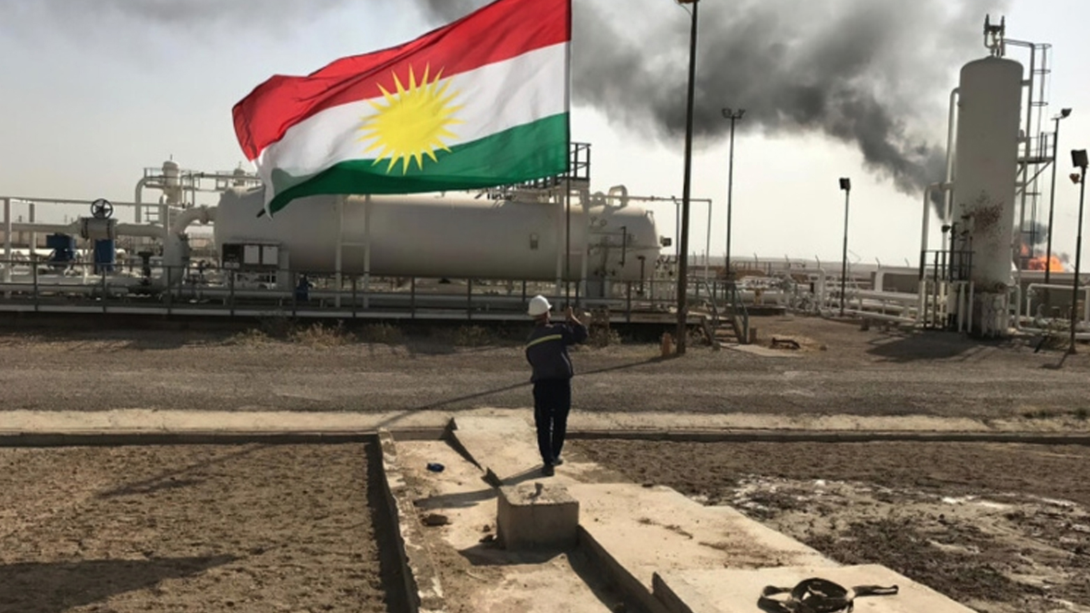 A staff at an oil-field holds the flag of Kurdistan. (Photo: Kurdistan24)
