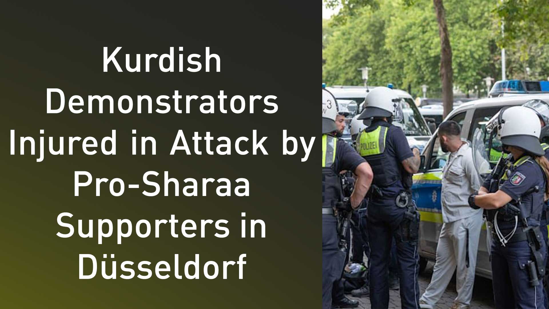 A group of German police officers in riot gear standing near police vans on a city street in Düsseldorf, Germany, July 21, 2025. (Photo: Designed by Kurdistan24)