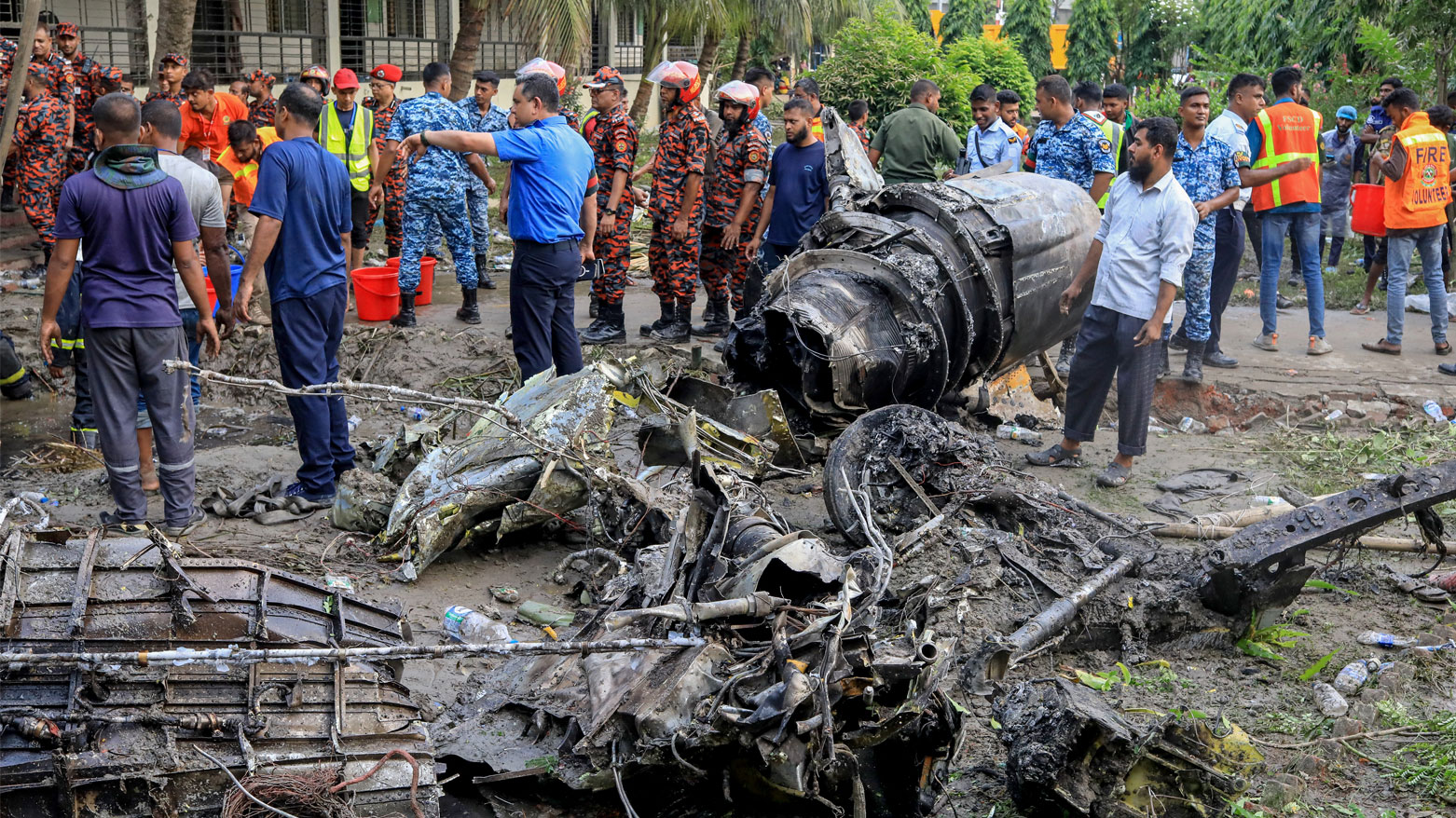 رجال الإطفاء والأمن في بنغلاديش في مكان تحطم طائرة تدريب تابعة للقوات الجوية في مدرسة بدكا (فرانس برس)