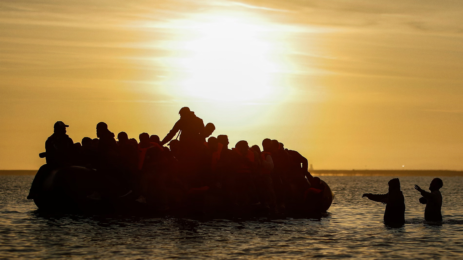 Migrants get onboard an inflatable dinghy to cross the Channel in Gravelines, northern France. (The Guardian)