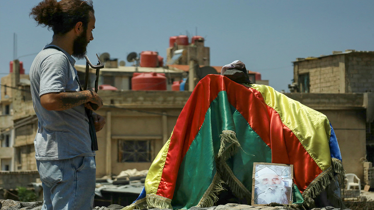 A Druze fighter stands at a roundabout draped with the Druze flag and a portrait of a local leader in the predominantly Druze city of Sweida in southern Syria on July 21, 2025. (Photo: AFP)