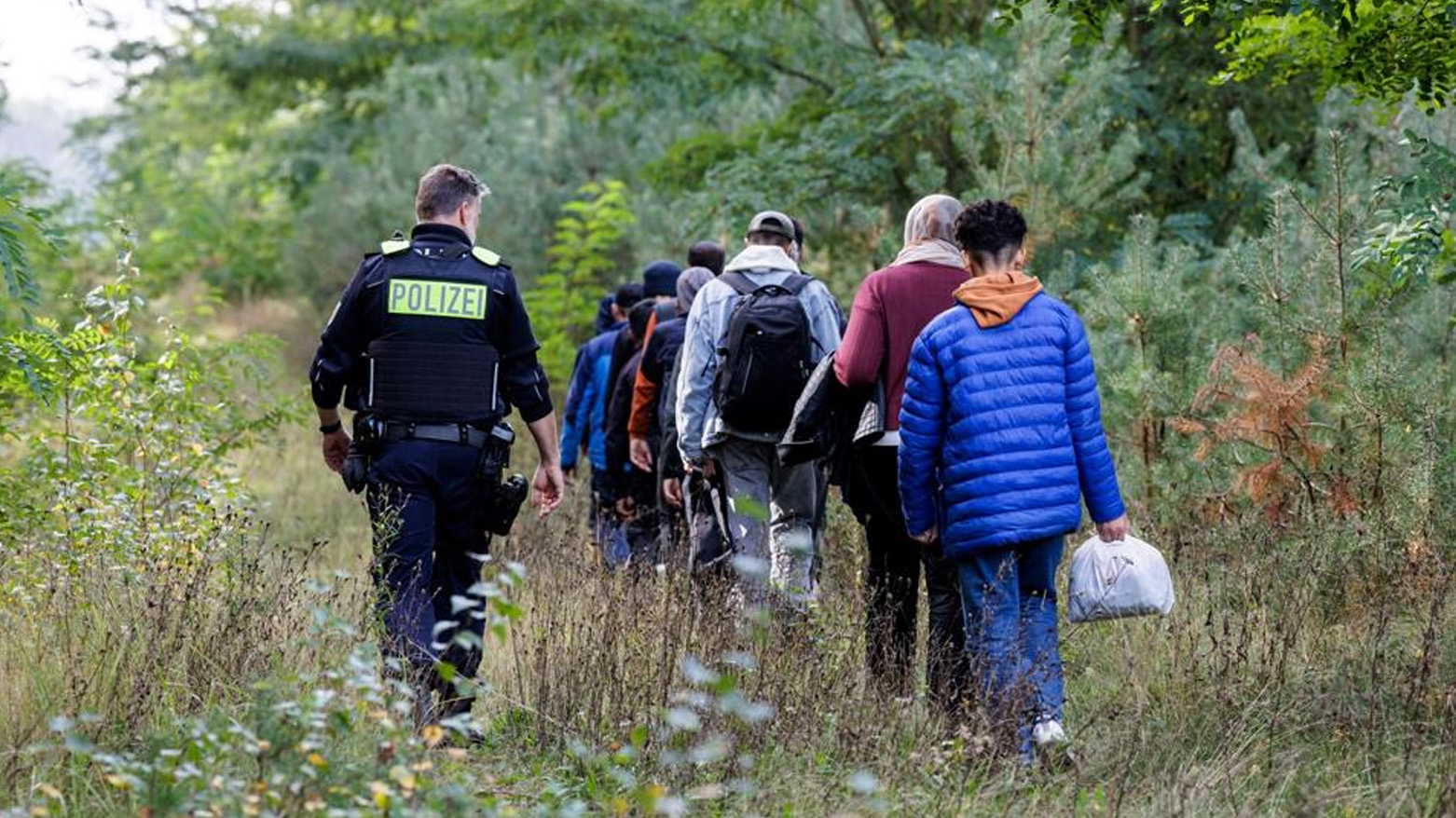 An officer of the German Federal Police (Bundespolizei) escorts a group of migrants near Forst, eastern Germany on Oct. 11, 2023. (Photo: AFP)