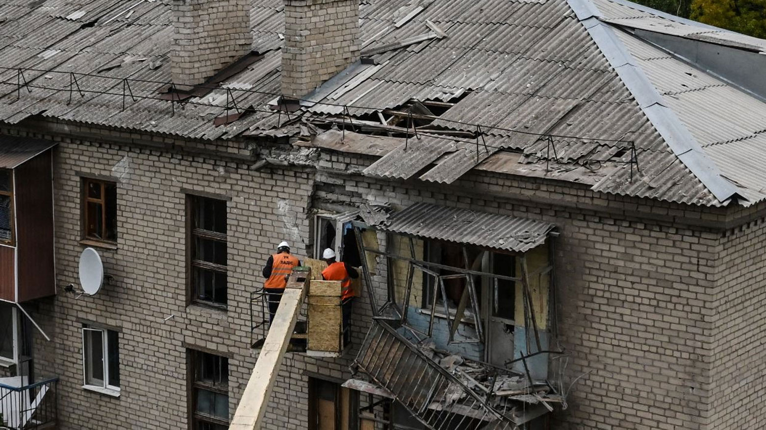 عمال بلديون يصلحون واجهة مبنى سكني متضرر بمنطقة دونيتسك (تعبيرية- فرانس برس)