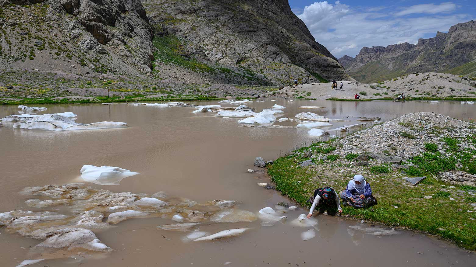 A woman touches a piece of melting ice on the Cilo glacier of Türkiye's southeastern Hakkari province, July 13, 2025. (Photo: AFP)
