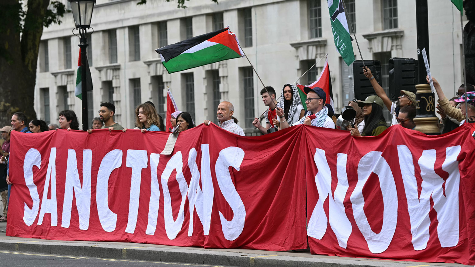 متظاهرون في لندن يحملون لافتة تدعو لفرض عقوبات على إسرائيل خلال مظاهرة دعمًا لغزة (فرانس برس)