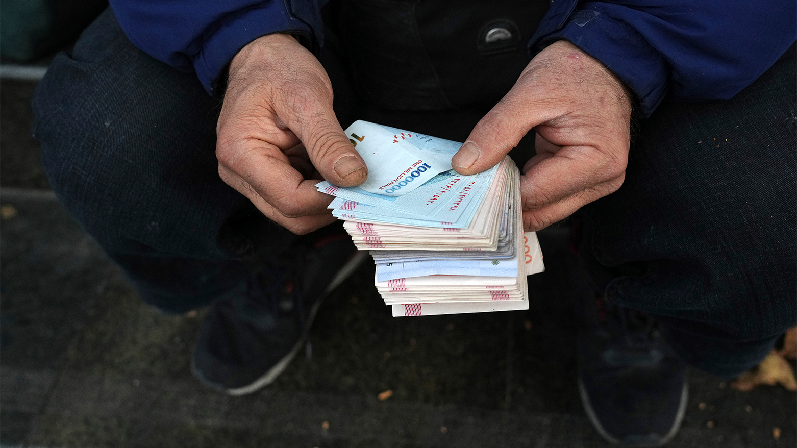A street money exchanger counts Iranian banknotes in downtown Tehran, Dec. 23, 2022. (AP)