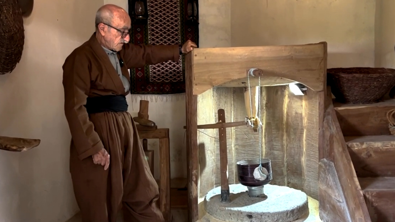 Zain al-Din Sahib Muhammad, a native of Hawraman area, standing in front of the historic water mill. (Photo: Kurdistan24)
