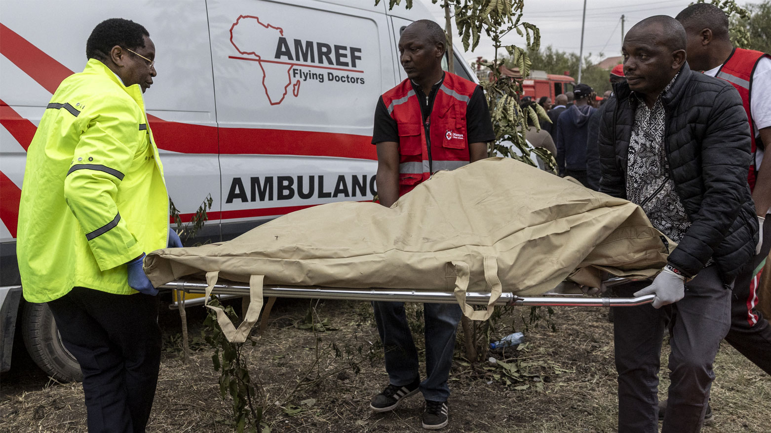 يحمل رجال الإنقاذ كيسًا للجثث يحتوي على بقايا بشرية من موقع تحطم طائرة طبية كينية (فرانس برس)