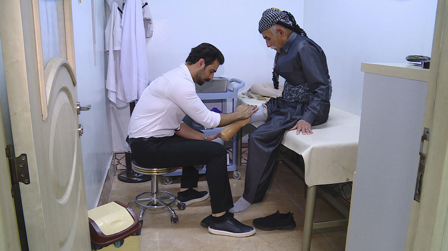 A prosthetics and orthotics specialist helps a patient put on a new prosthetic leg. (Photo: Kurdistan24)