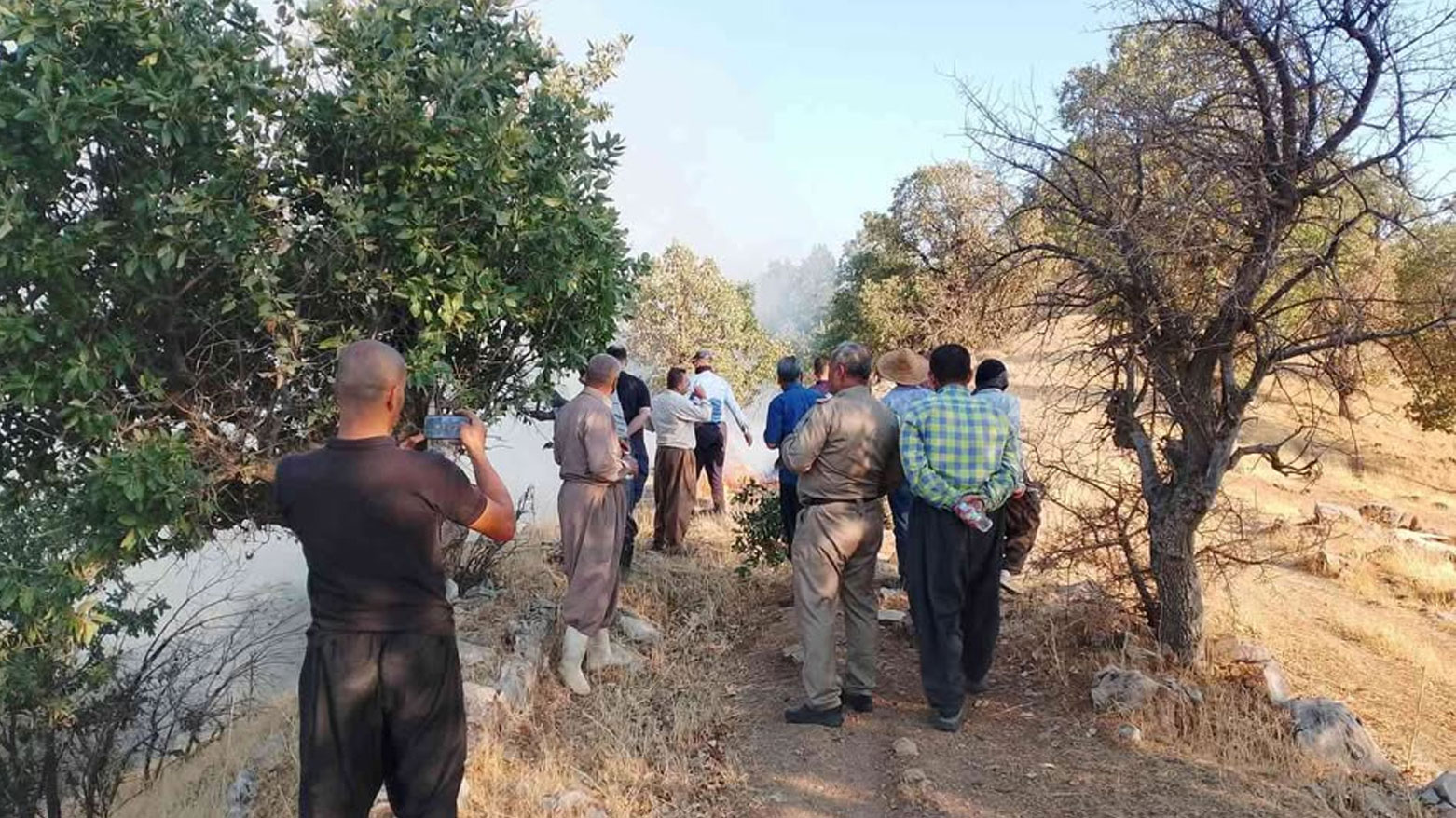 A photo shows local residents trying to extinguish a fire that broke out in the Sharba­zher area. (Photo: Kurdistan24)