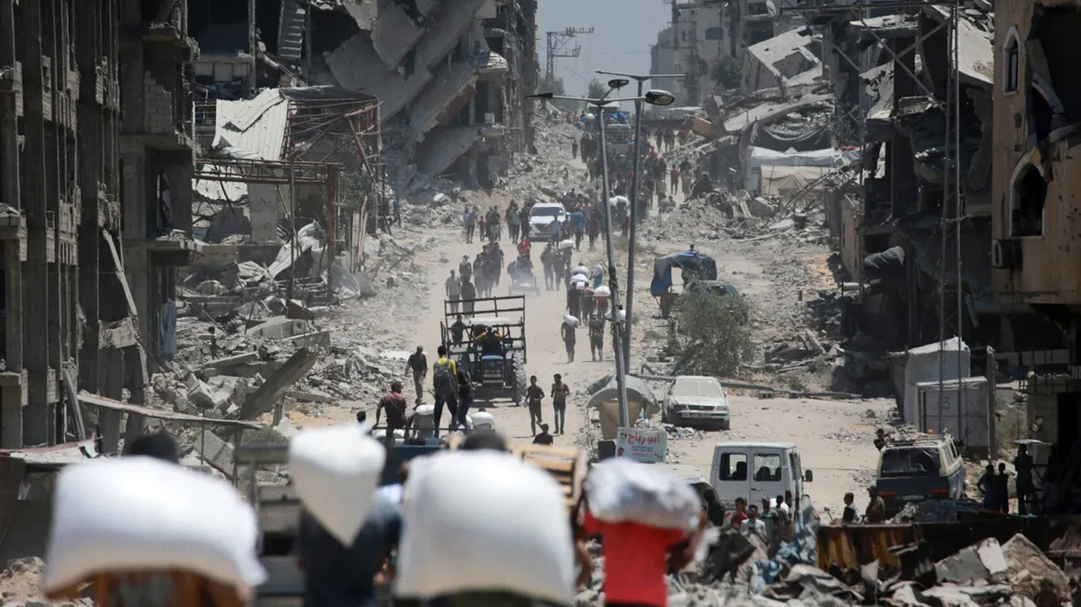 Palestinians carry bags of flour from aid trucks in Jabalia in the northern Gaza Strip, on Aug. 1. (AFP)
