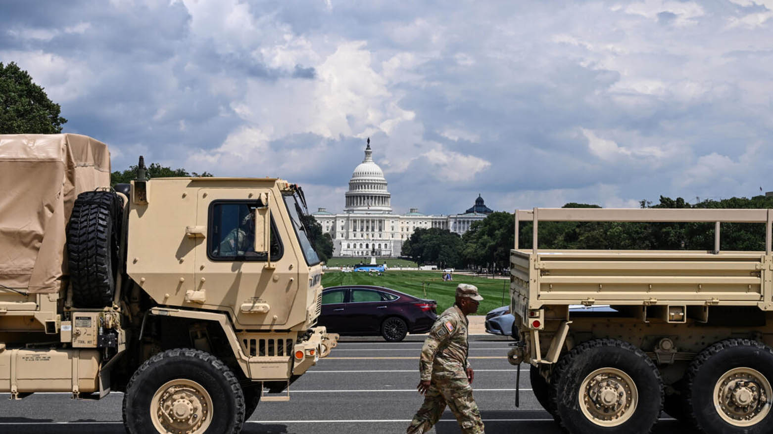 یکی از اعضای گارد ملی ایالات متحده در حال عبور از کنار خودروهای نظامی در نشنال مال واشنگتن – عکس: ای‌اف‌پی