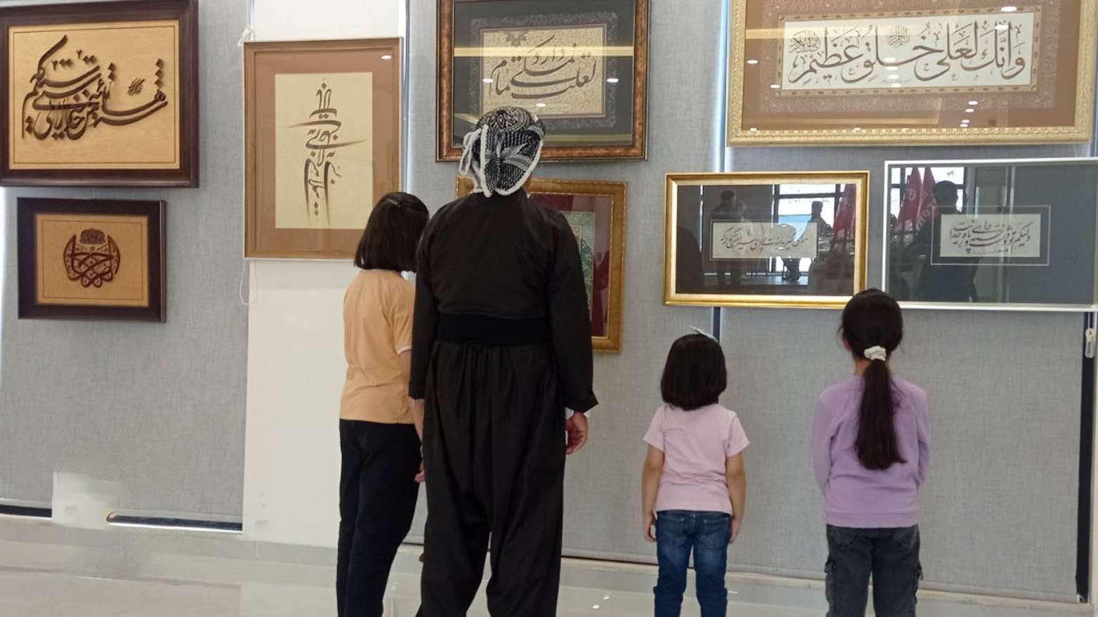 A Kurdish man and three youths admire Kurdish calligraphy on display. (Photo: Kurdistan24)