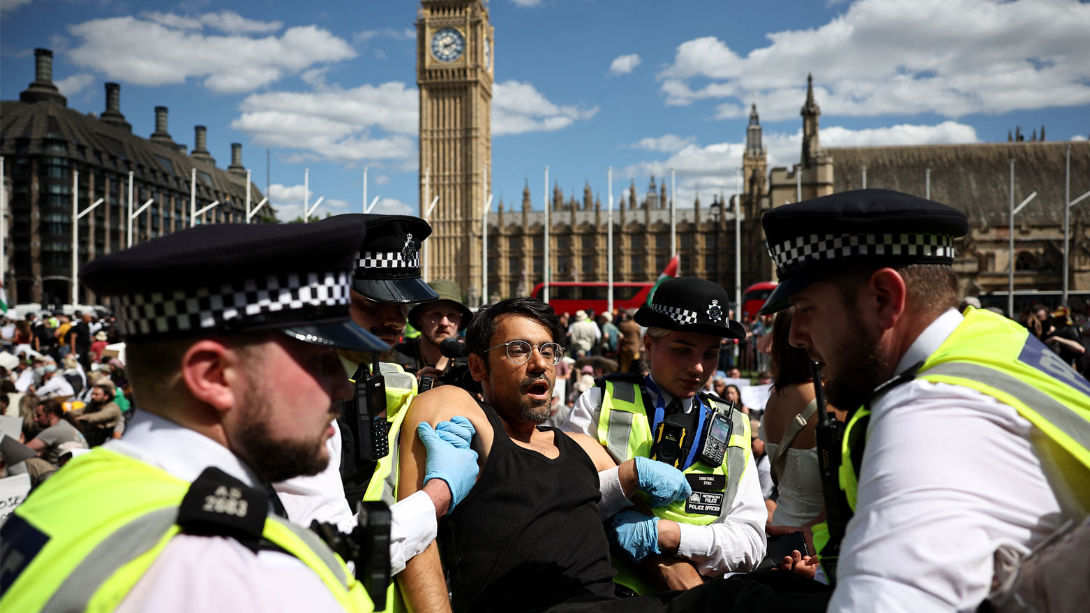 الشرطة تقتاد متظاهرًا في مظاهرة "ارفعوا الحظر" في ساحة البرلمان بوسط لندن (فرانس برس)
