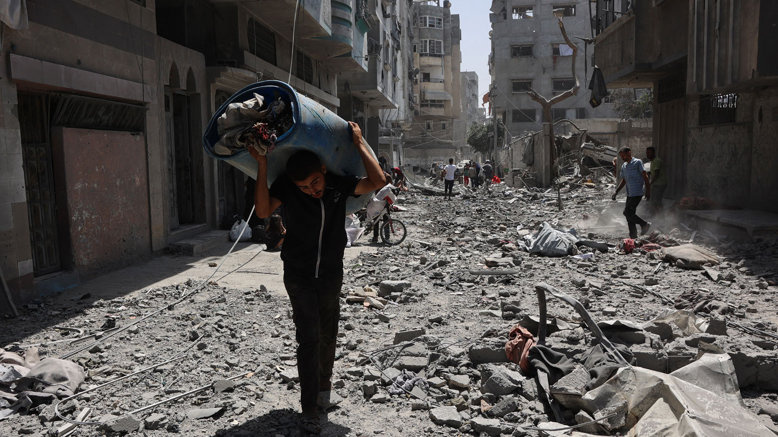 فلسطينيون ينقذون أغراضًا من أنقاض منازل دُمرت جراء غارات إسرائيلية بمدينة غزة (فرانس برس)