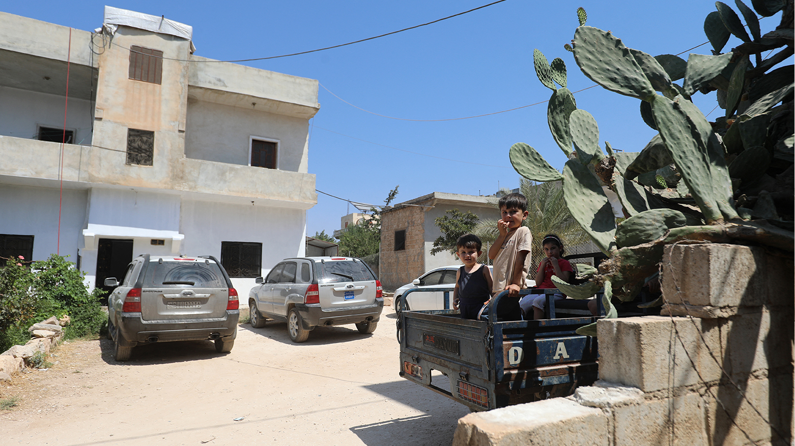 Children sit in the bed of a truck in front of a house, the site of a reported operation by the US-led coalition, in the town of Atme in northwestern Syria on Aug. 20, 2025. (AFP)