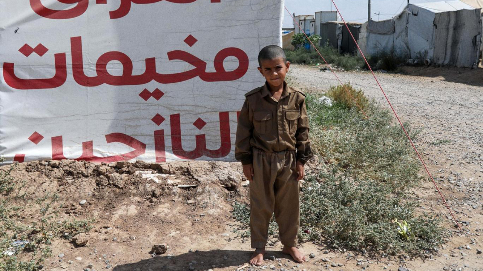 A child poses at the Hasan Sham camp for displaced persons, 40 km west of Erbil, Sept. 17, 2024. (AFP)