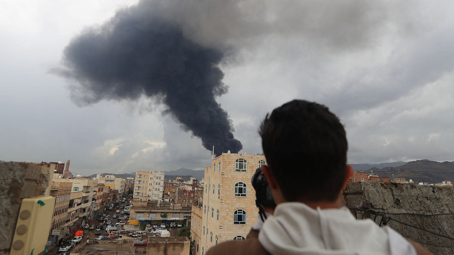 A photojournalist takes a picture of smoke after an Israeli air strike on Yemen's Huthi-held capital Sanaa on August 24, 2025.