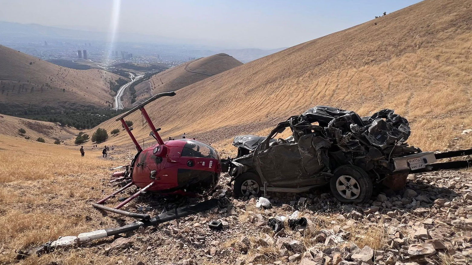 The photo shows the crash site of a rescue helicopter beside the car that plunged off the cliff. (Photo: Kurdistan24)