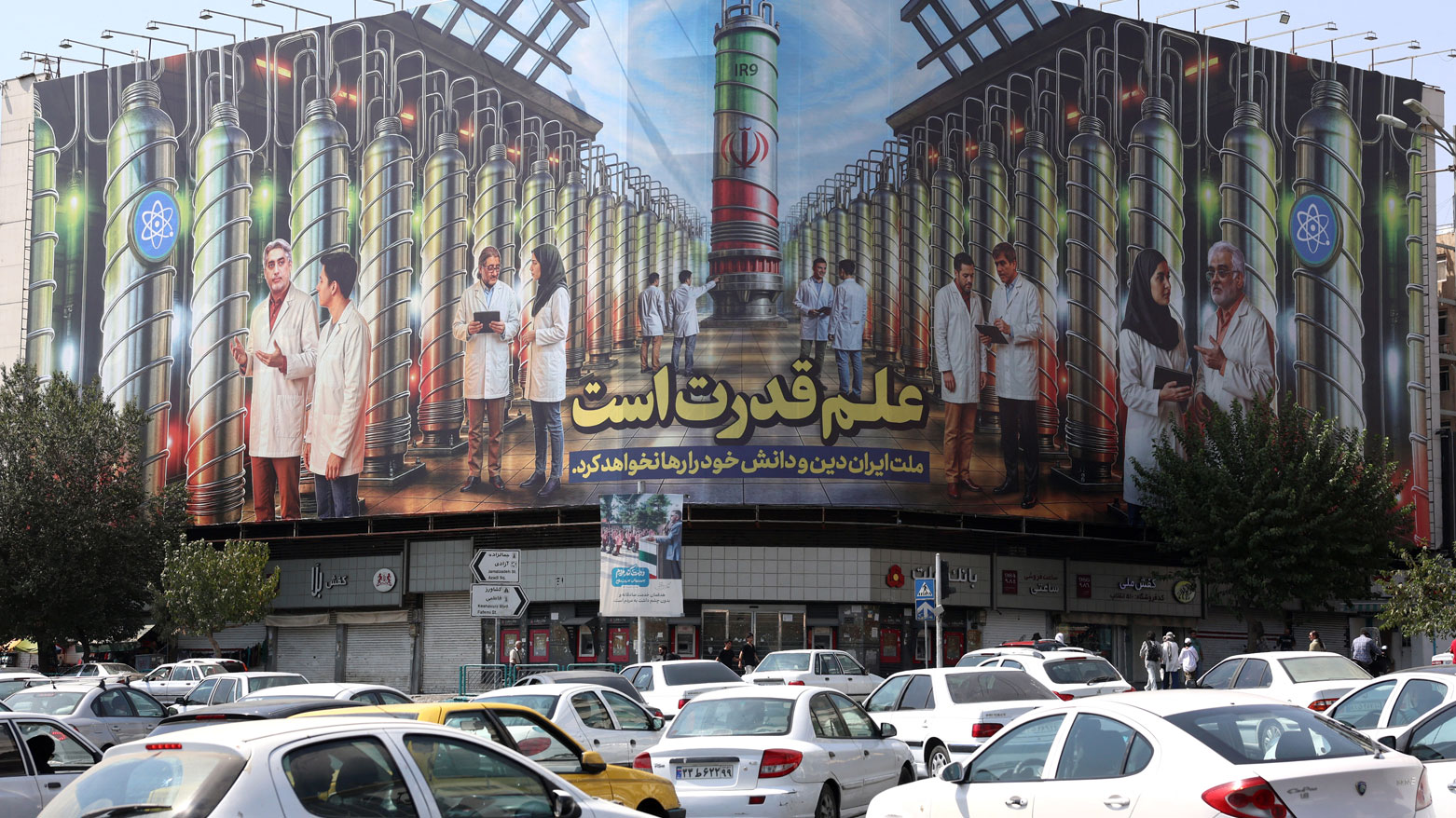 لوحة إعلانية في ساحة انقلاب بطهران تعرض صوراً لعلماء نوويين وأجهزة طرد مركزي (فرانس برس)