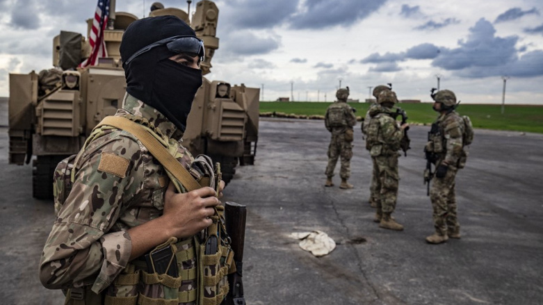 A member of the Syrian Democratic Forces (SDF) (L) and US soldiers are pictured near an armoured military vehicle in Syria (AFP)