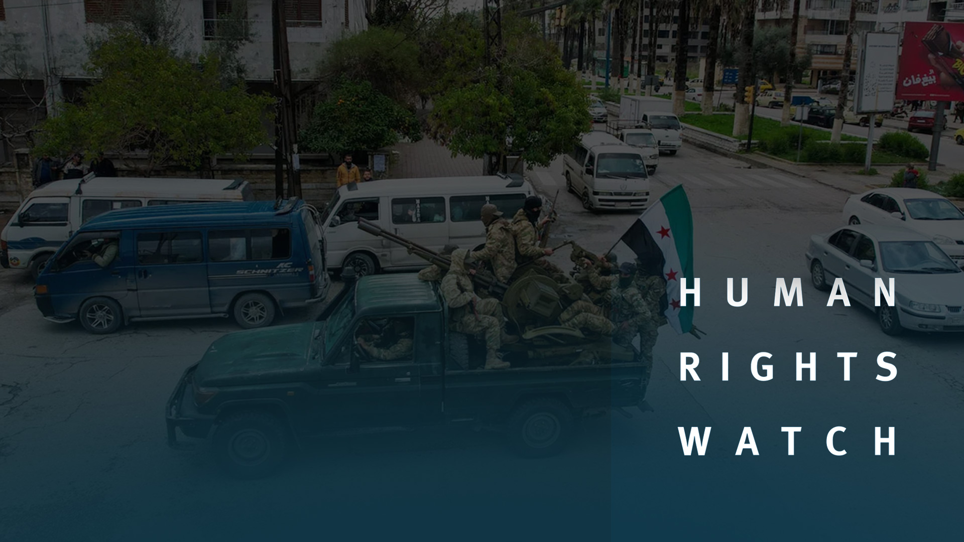 Human Rights Watch logo and Syrian soldiers inside a military vehicle raise the Syrian flag in the background. (Graphic: Kurdisan24)