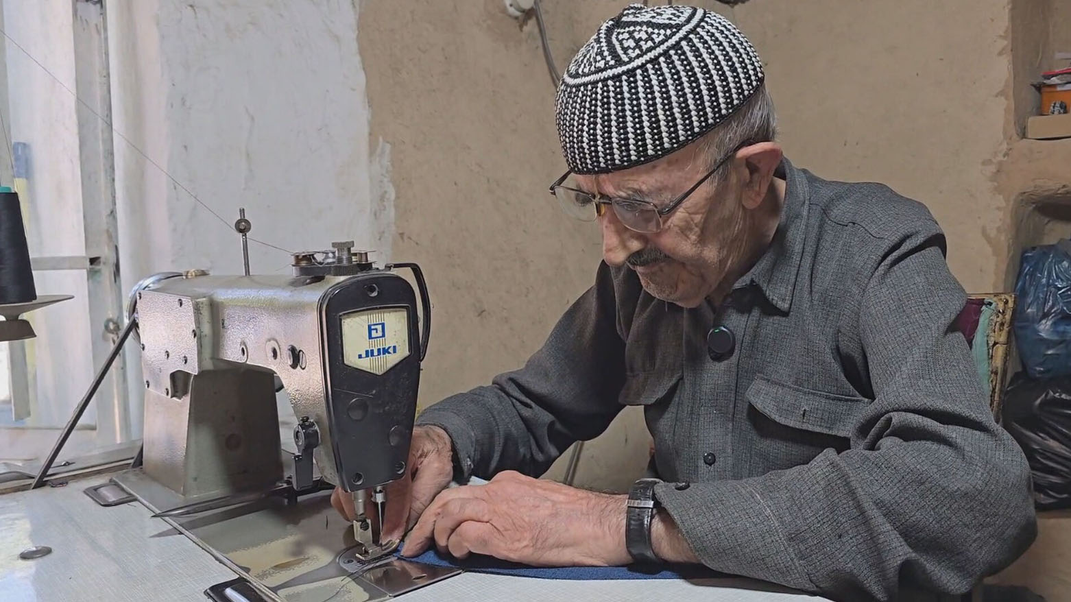 The photo shows Wasta Mustafa sitting and working behind his sewing machine. (Photo: Kurdistan24)