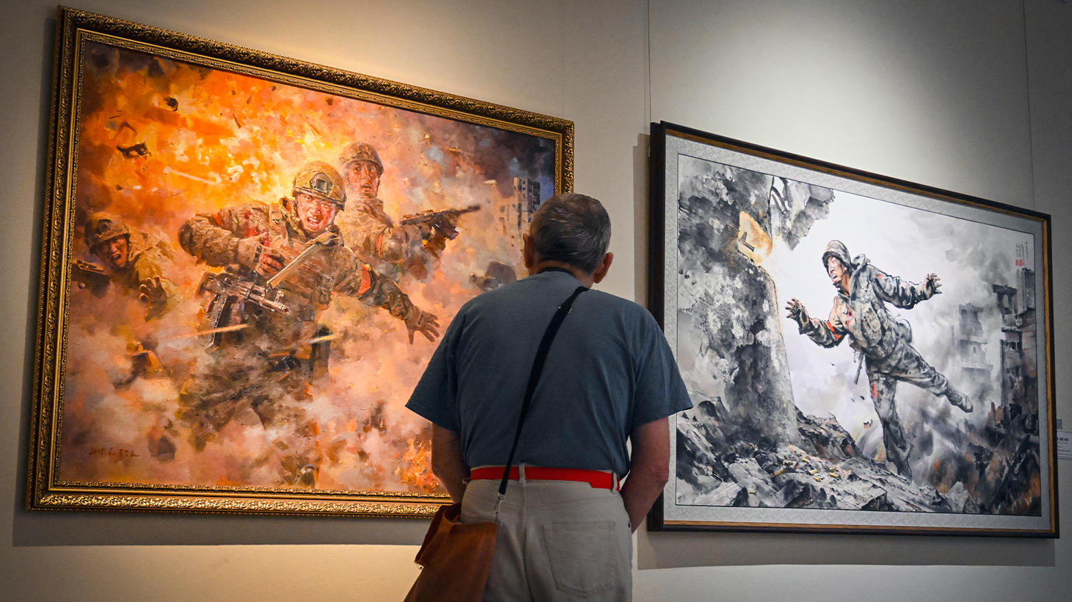 A visitor walks by the paintings displayed at the art gallery. (AFP)