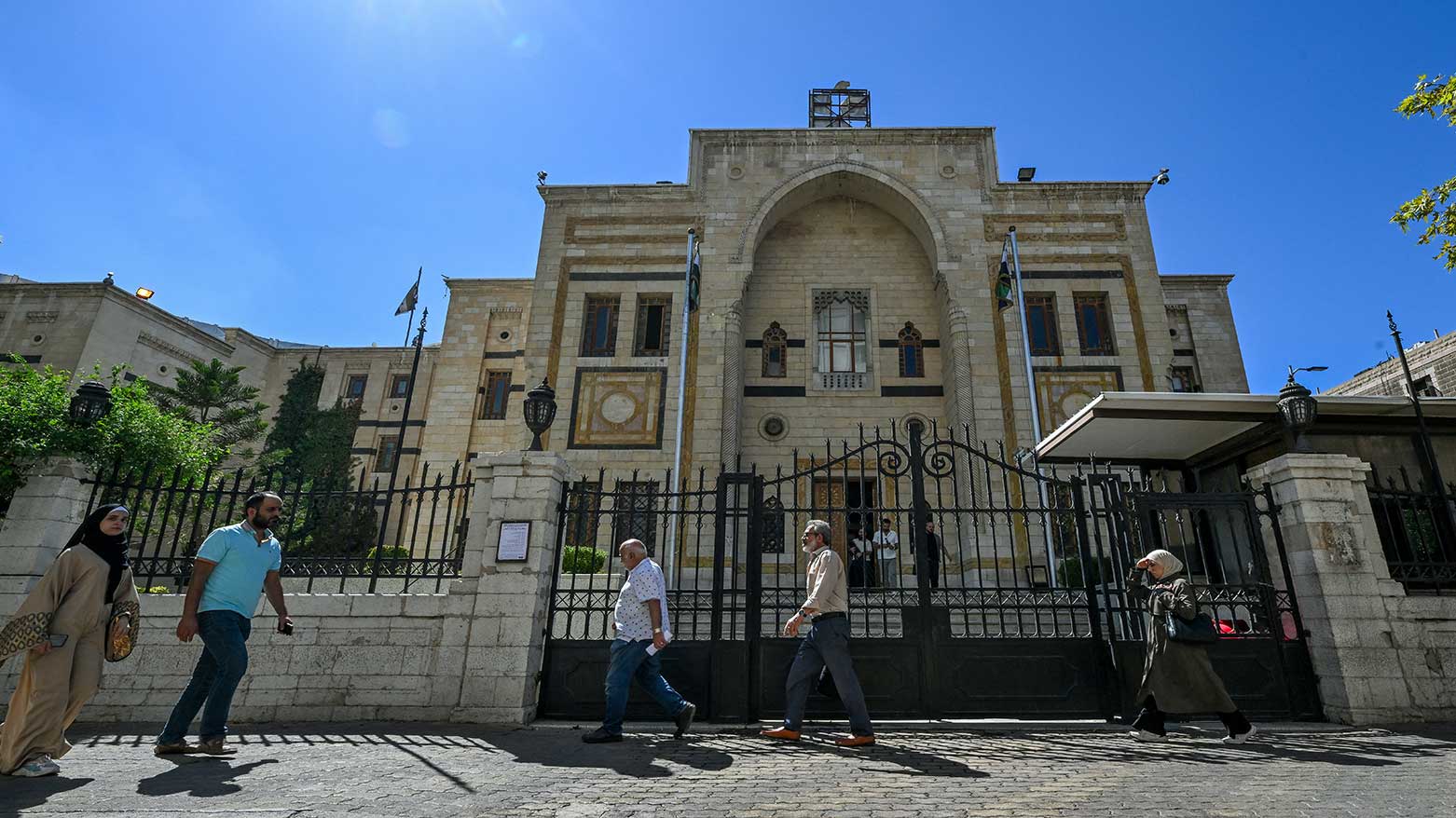 People walk past the parliament building in Damascus on October 1, 2025. (Photo: AFP)