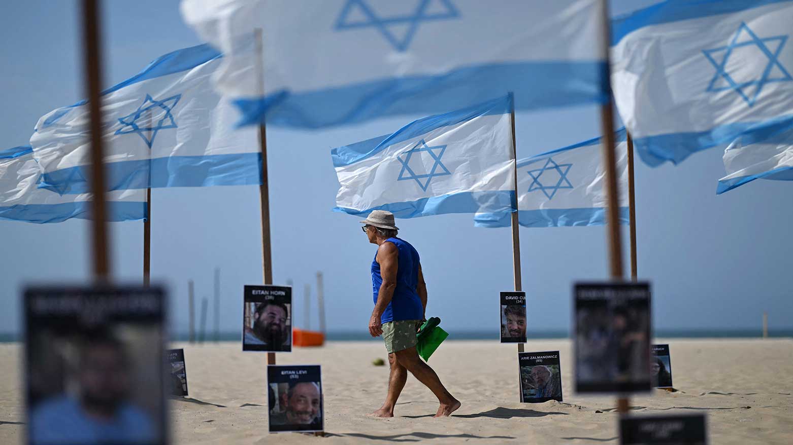 A man walks amid Israeli flags and names of victims displayed by Brazilian NGO Rio de Paz, marking the second anniversary of the attacks by Hamas, at Copacabana Beach in Rio de Janeiro, Brazil, on October 7, 2025.