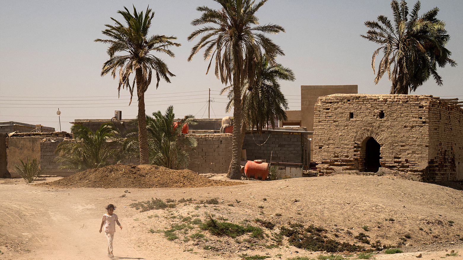A girl walks abandoned buildings, north of Basra in southern Iraq on Sep.13, 2025. (AFP)