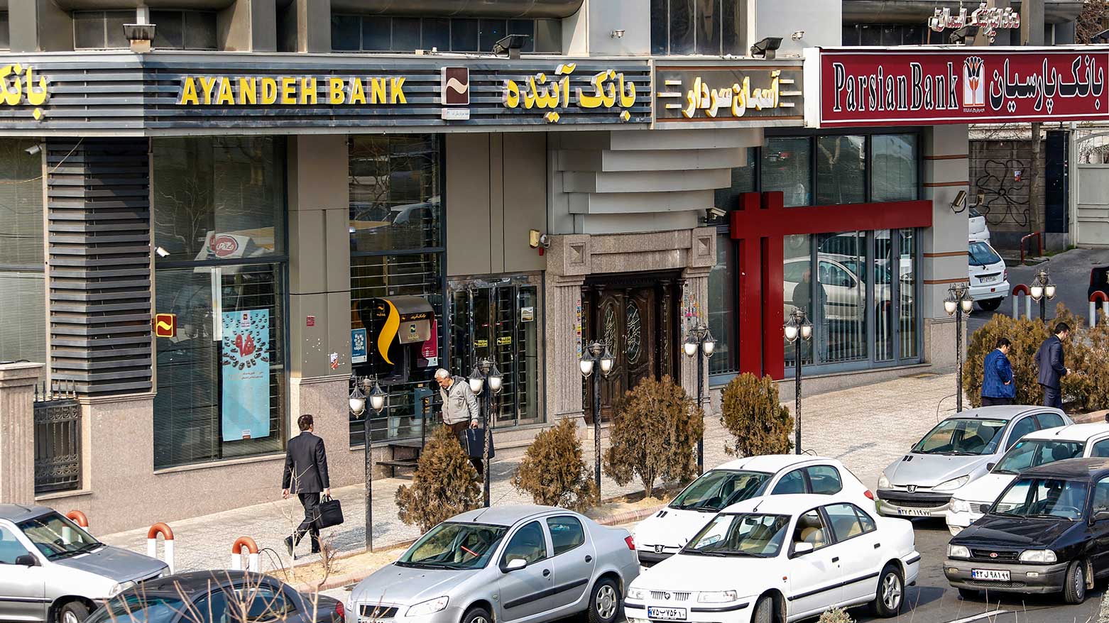 Iranians walk past an Ayandeh Bank branch (L) in the capital Tehran on January 14, 2017. Iran  on Oct. 25, 2025 declared Ayandeh Bank bankrupt with its assets absorbed by the state. (Photo: AFP)