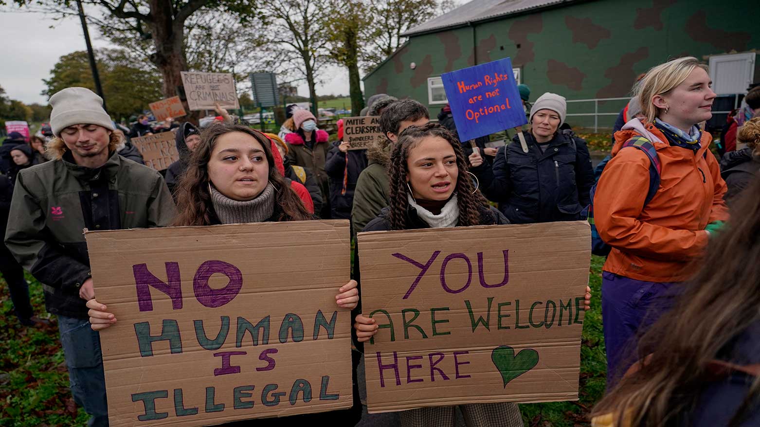 Demonstrators hold placards as they take part to a protest outside the Manston immigration short-term holding facility near Thanet, Kent, England, Nov. 6, 2022. (Photo: AP)