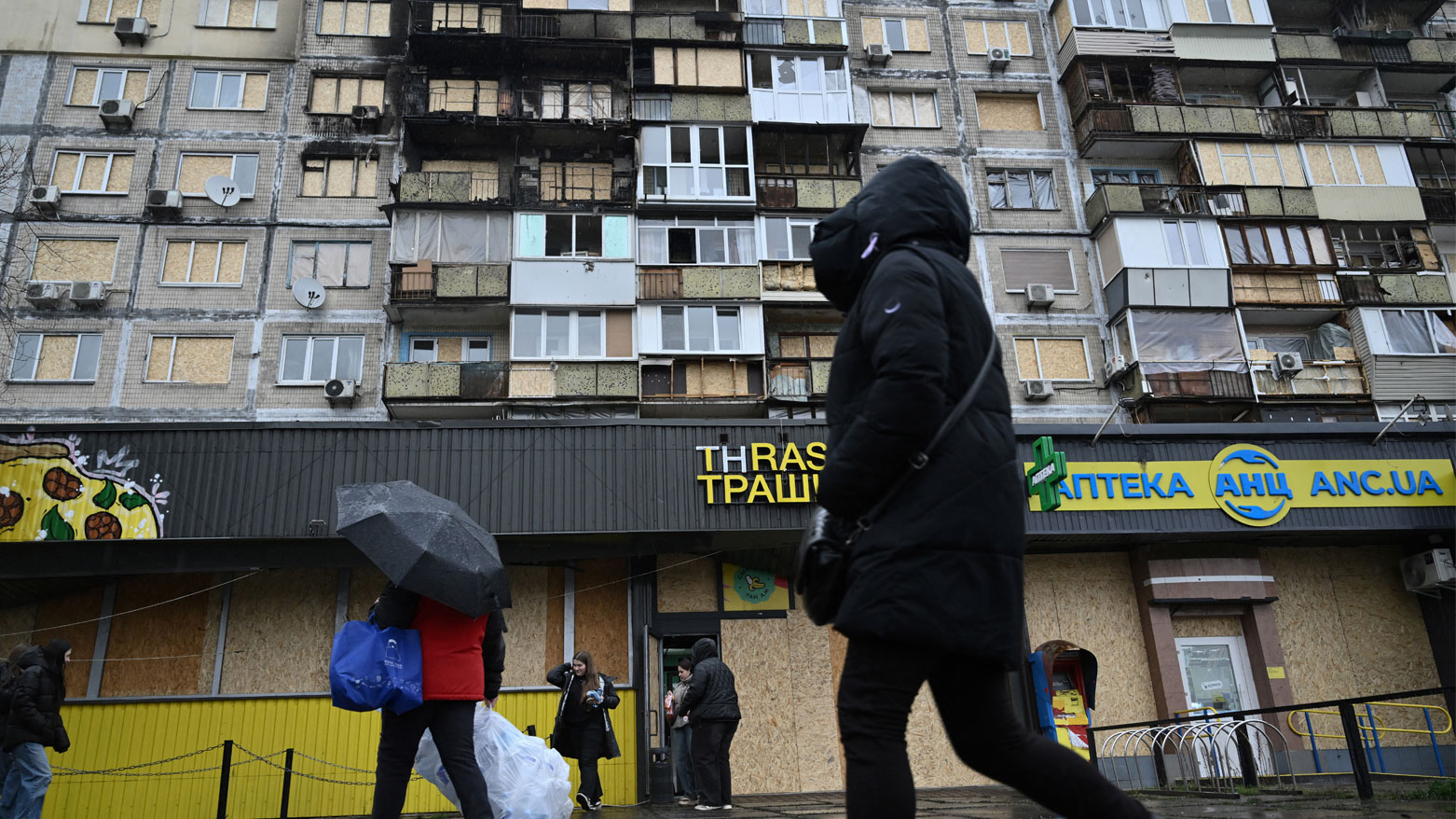 أشخاص يسيرون أمام مبنى سكني تضرر جراء غارة جوية حديثة في كييف (فرانس برس)
