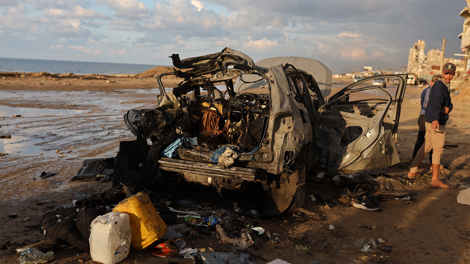 Palestinians inspect the site of an Israeli strike on a car in Gaza City, on December 13, 2025. (AFP)