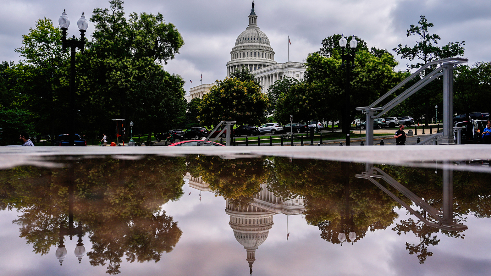 The U.S. Capitol is reflected in a puddle outside of the Rayburn House Office Building, July 16, 2025, Washington. (AP)