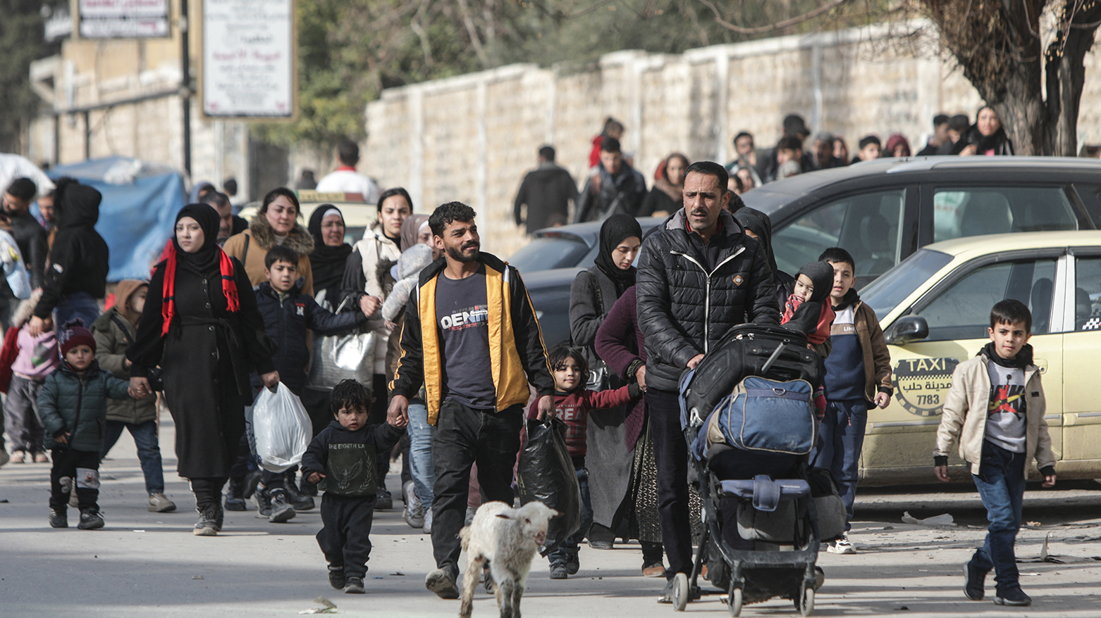 Residents carry their belongings as they flee Aleppo's Ashrafieh Kurdish neighbourhood on Jan. 7, 2026. (AFP)
