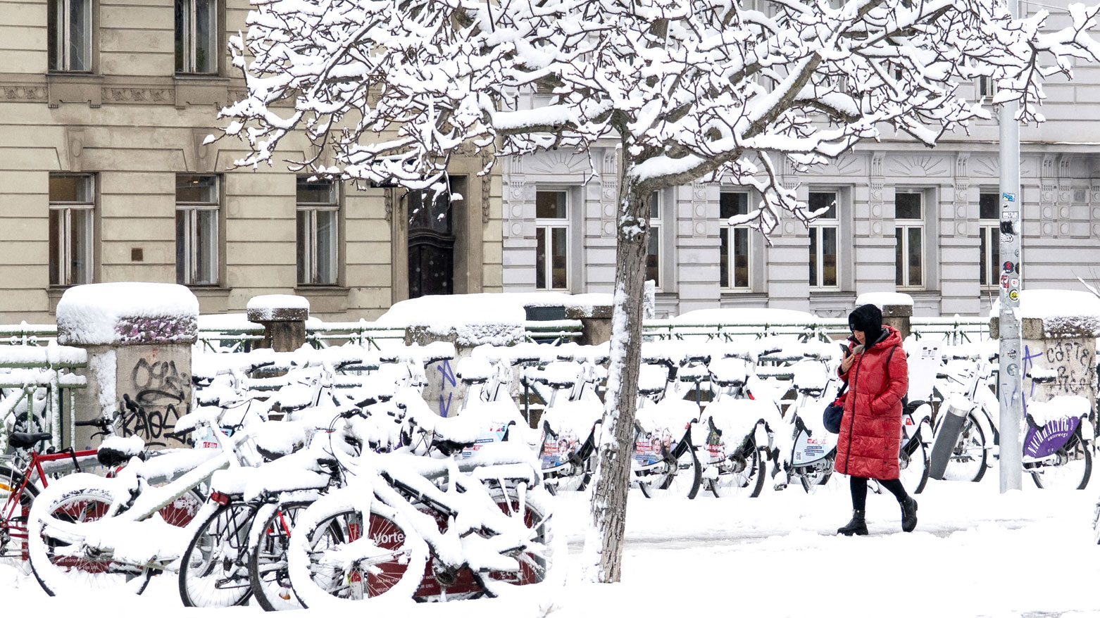 امرأة تسير في شارع مغطى بالثلوج بينما يضرب الشتاء فيينا بالثلوج ودرجات الحرارة المتجمدة (فرانس برس)