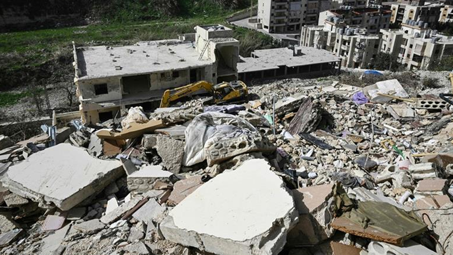 A damaged excavator sits on the rubble of a building that was hit in January by an Israeli strike in the southern Lebanese village of Qannarit, on Feb. 16, 2026. (AFP)