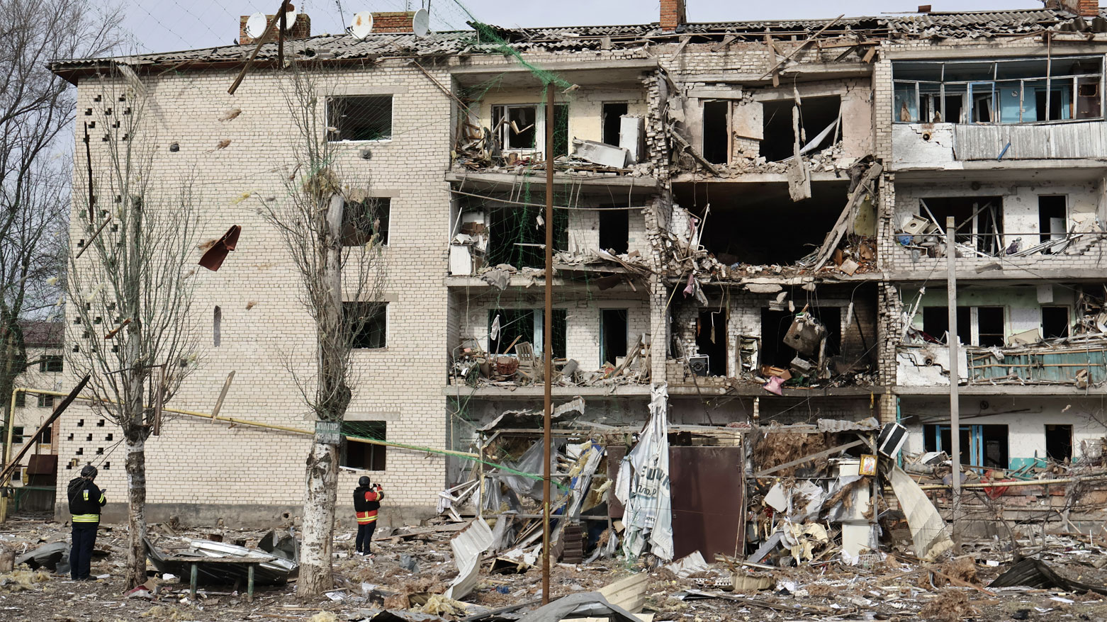 عناصر إنفاذ القانون الأوكرانيين يقفون بين أنقاض مبنى سكني متضرر في أعقاب هجوم جوي في كوميشوفاخا، منطقة زابوريزهيا (فرانس برس)