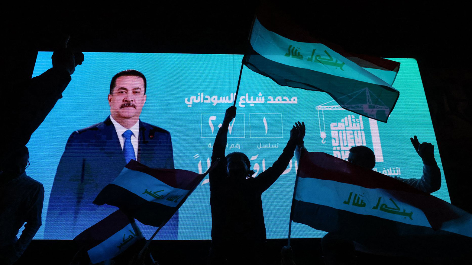 Supporters of incumbent Iraqi PM Mohammed Shia al-Sudani wave national flags in front of a screen displaying his portrait as they celebrate his victory in the elections, in Baghdad, Nov. 12, 2025. (AFP)