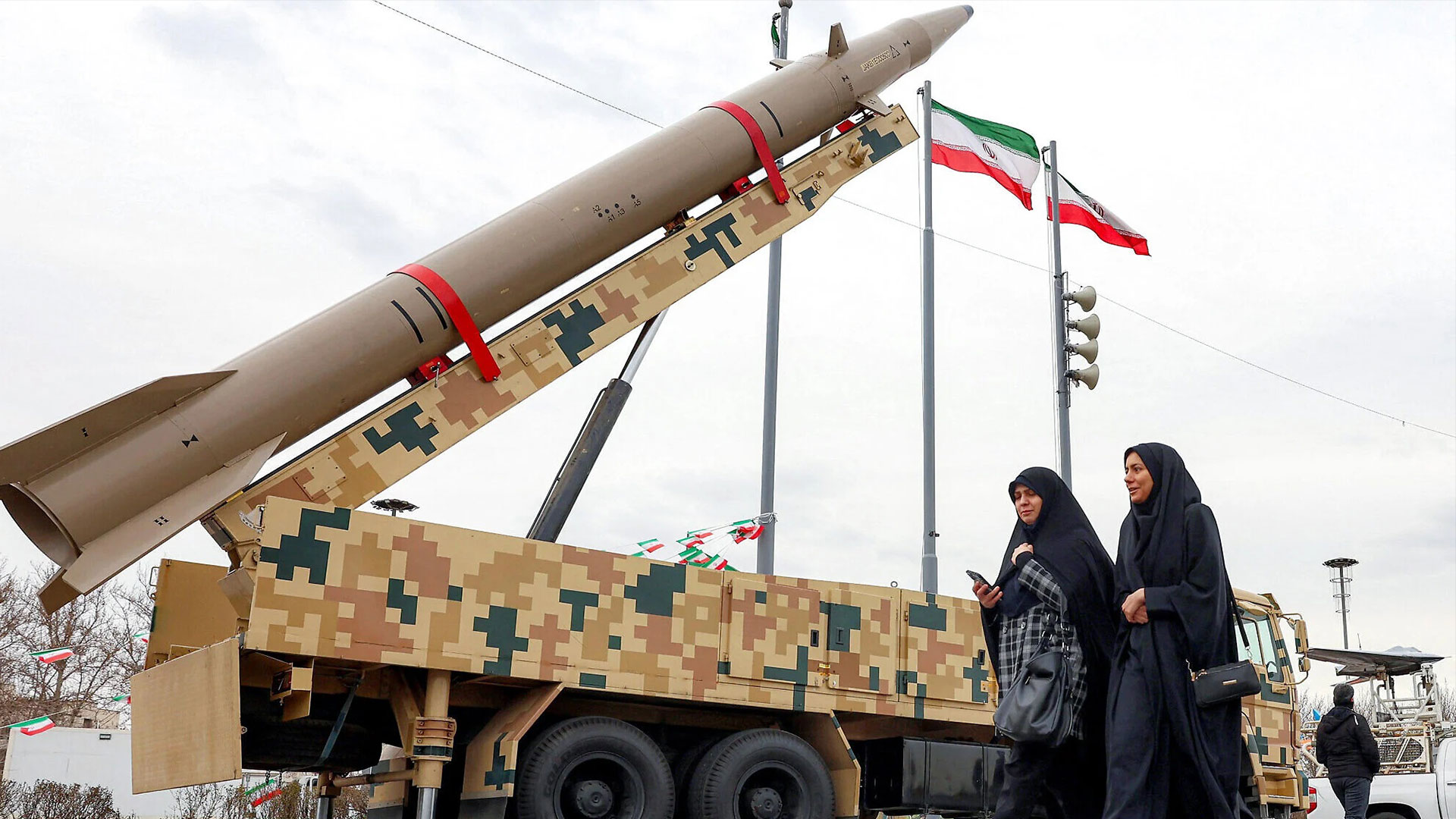 Women walk near ballistic missile launch vehicles in Tehran on February 11, 2026, during a rally marking the 47th anniversary of the 1979 Islamic revolution. (Photo: AFP)