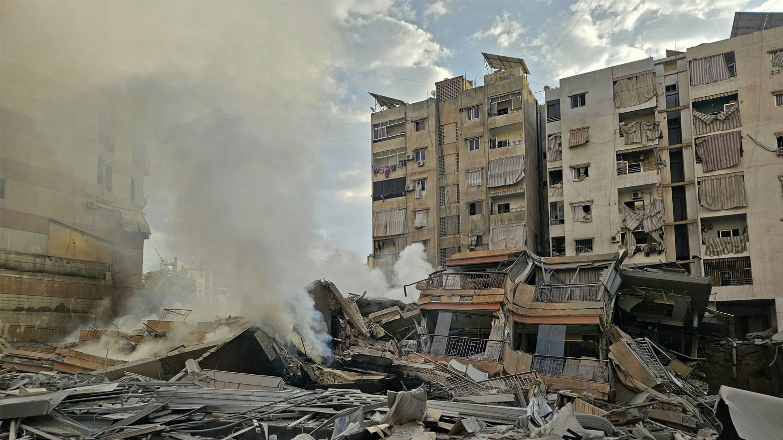 يتصاعد الدخان من أنقاض المباني المدمرة في موقع غارة جوية إسرائيلية استهدفت حي حارة حريك في الضواحي الجنوبية لبيروت (فرانس برس)