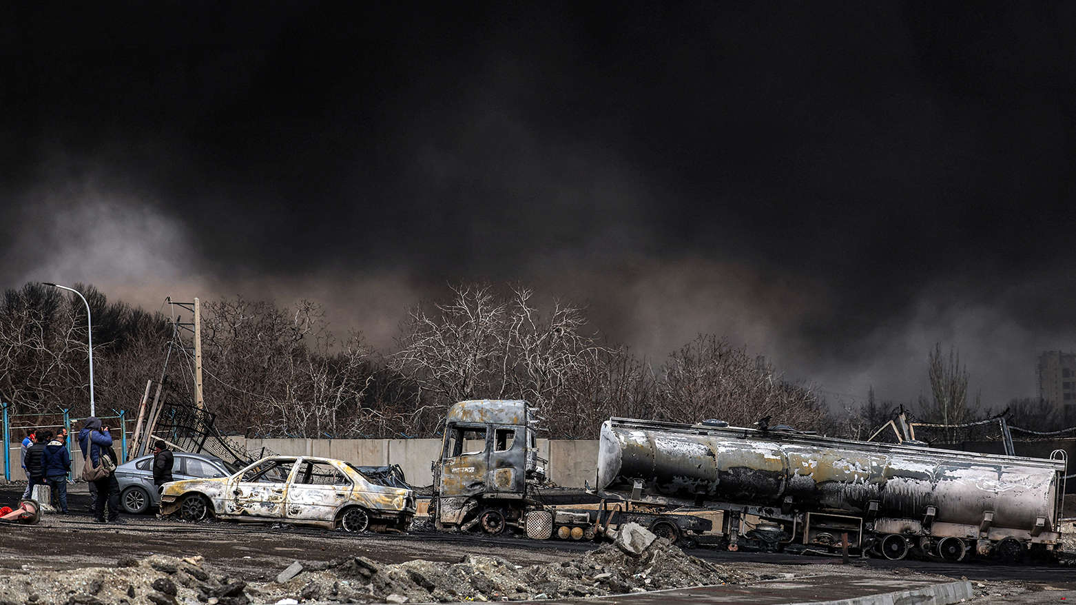 A dark smoke cloud engulfs destroyed vehicles near an ongoing fire following an overnight airstrike on the Shahran oil refinery, Tehran on March 8, 2026. (AFP)