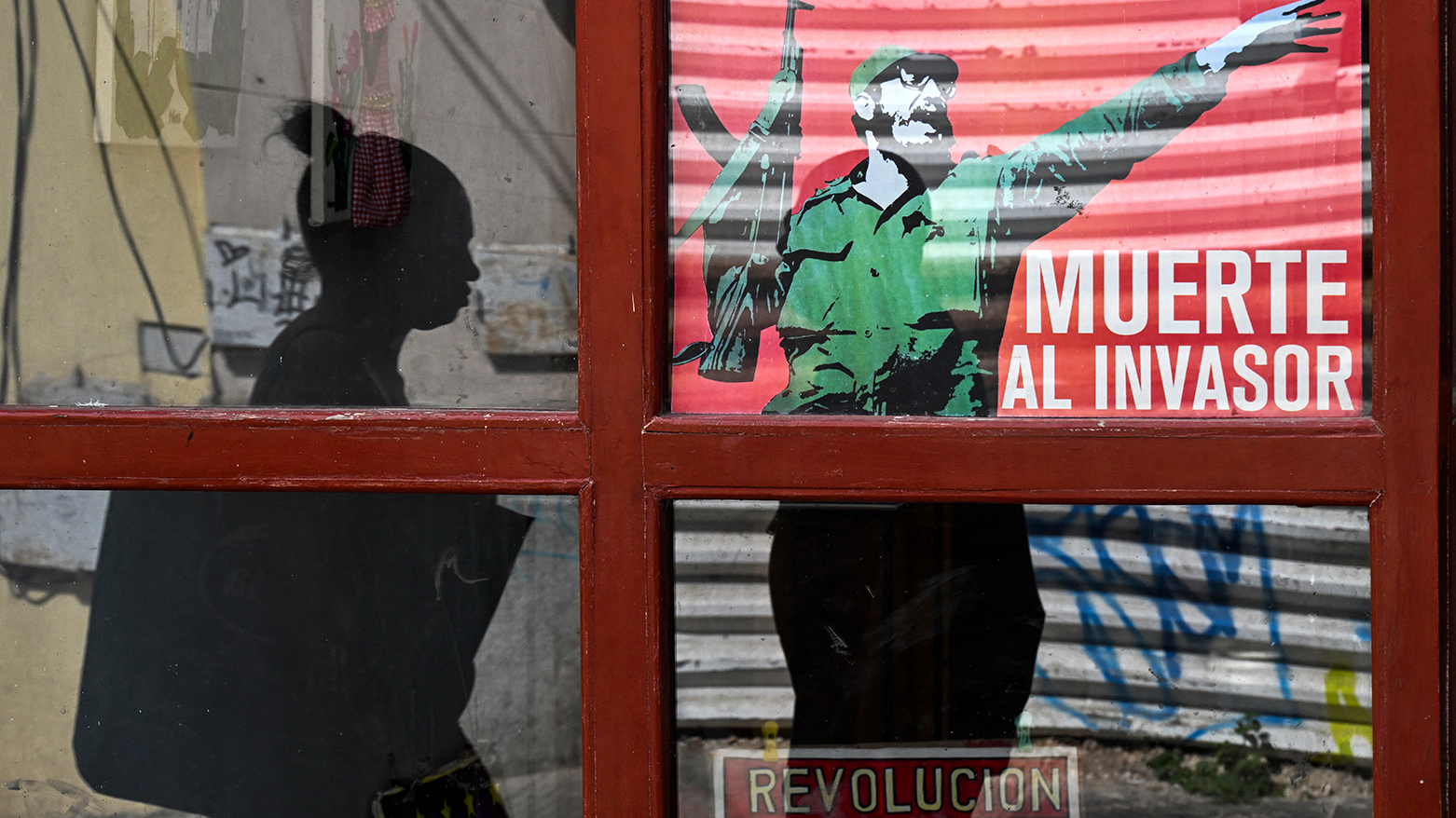 A woman walks past a poster of late Cuban leader Fidel Castro reading "Death to the invader" in Havana on March 13, 2026. (AFP)