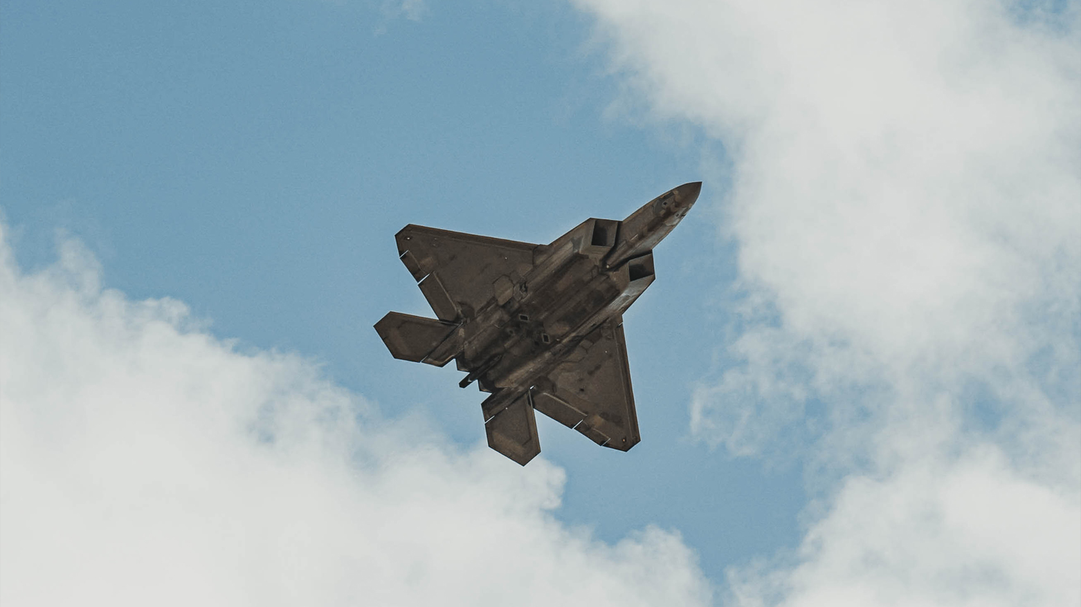 A U.S. Air Force F-22 Raptor performing a high-angle climb against a partly cloudy sky. (Photo: CENTCOM)