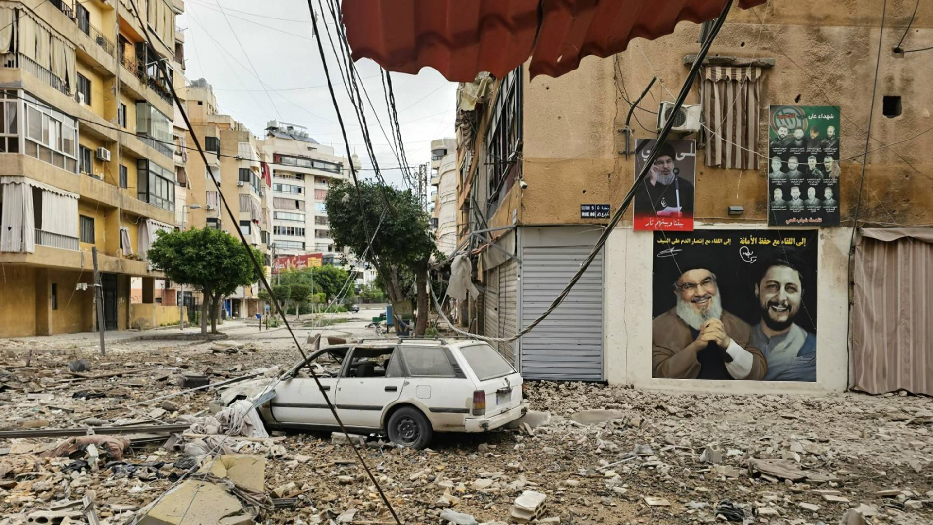 A banner of assassinated Hezbollah leader Hassan Nasrallah hangs amid rubble in Beirut’s southern suburbs following an Israeli airstrike on Mar. 25, 2026. (AFP)
