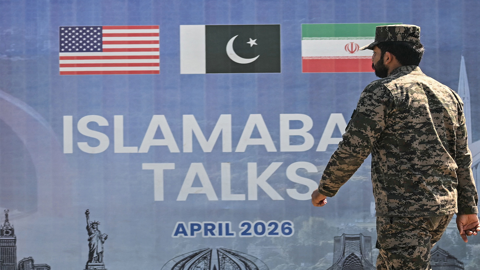 A Pakistani Ranger walks past a billboard for the US-Iran peace talks in Islamabad on April 12, 2026. (AFP)